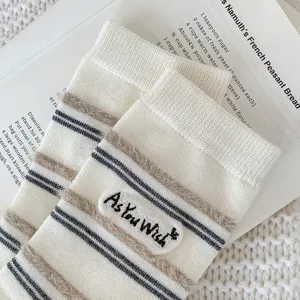 Close-up of cream-colored striped socks with 'As You Wish' fuzzy embroidered patch