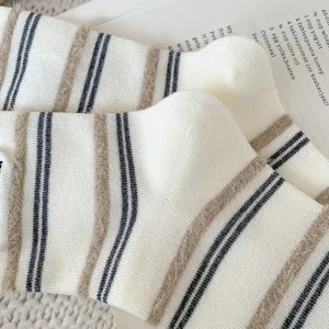 Close-up detail of white mid-calf socks featuring beige fuzzy stripes and navy lines