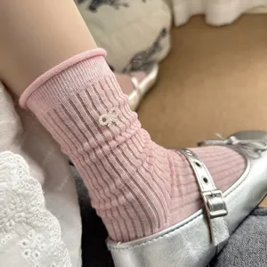 Close-up detail showing the texture of cute pink ribbed crew socks with a pearl bow
