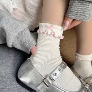 Detailed view of girl's white ruffle socks with pink bowknot and silver Mary Janes