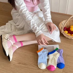 Detailed shot of breathable candy color hollow socks on wooden floor with fruit basket prop.