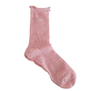 Cute pink mid-calf socks for women featuring ruffled edges and a small white bow detail