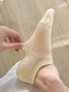 Macrodetail van het ademende gaaspatroon op een dunne beige onzichtbare enkelsok