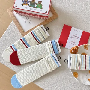 Gros plan de chaussettes à volants crème avec rayures rouges et bleues