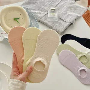 Macro-weergave van hand die ademende mesh onzichtbare sokken in pastelkleuren vasthoudt
