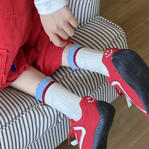 Détail de chaussettes en coton pour filles avec bords à volants bleus et baskets rouges