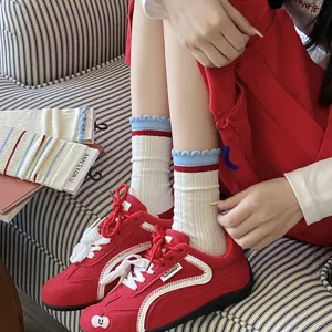 Vue détaillée de chaussettes en coton blanc avec froufrous rouge et bleu et baskets rouges