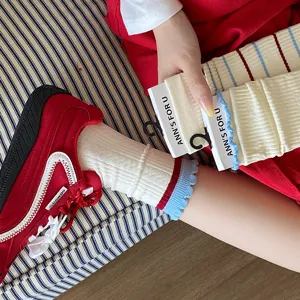 Gros plan de chaussettes côtelées crème avec rayures rouge/bleu et bords volantés
