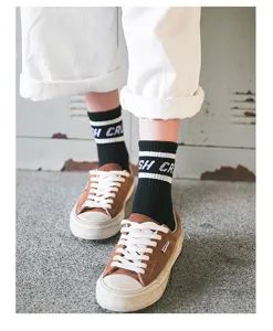 Close-up van zwarte katoenen sokken tot halverwege de kuit met witte strepen, streetwear.