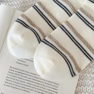 Close-up detail of white striped plush socks with warm fuzzy texture on a book
