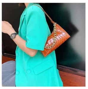 Bolso bajo el brazo marrón con patrón de cocodrilo y cadena dorada.