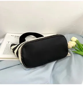 Vue détaillée du sac à main en paille tressée à rayures noires et blanches avec base