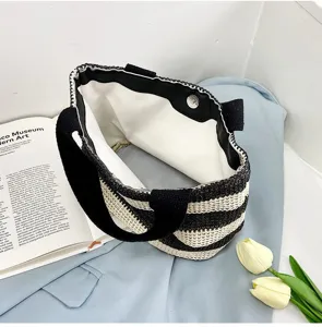 Détail d'un sac à main tissé à rayures noires et blanches avec doublure et fermoir.