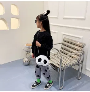 Λεπτομερής προβολή της λούτρινης τσάντας panda που φοράει ένα κορίτσι στο δωμάτιο