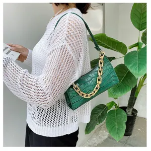 Vista detallada de un bolso de hombro verde con patrón de cocodrilo y cadena dorada gruesa