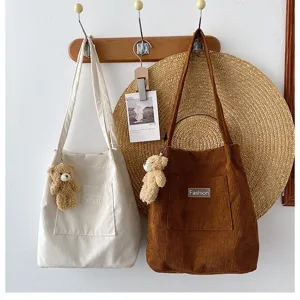 Detailansicht von Cord-Schultertaschen in Weiß und Braun mit süßen Teddybären-Anhängern.