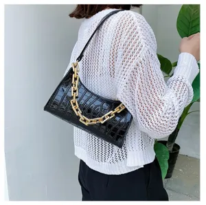 Primer plano de un bolso de hombro negro con diseño de cocodrilo y cadena dorada elegante.