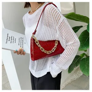 Bolso de hombro rojo con patrón de cocodrilo y cadena dorada usado por una modelo.