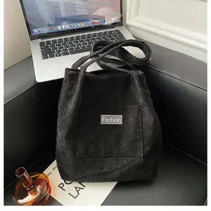 Große schwarze Beuteltasche aus Cord mit „Fashion“-Patch in einem modernem Lifestyle-Ambiente.