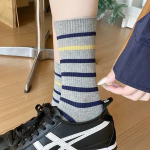 Detailed view of women's gray striped mid-calf socks paired with black sneakers