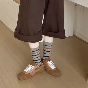 Detailed view of gray striped mid-calf socks paired with brown sneakers shoes