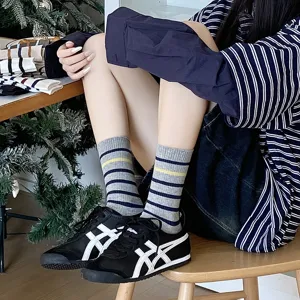 Close-up of stylish grey and yellow striped mid-calf socks worn by a model in sneakers