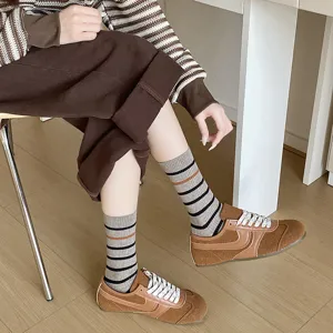 Close-up of stylish striped mid-calf socks for women worn with brown suede sneakers