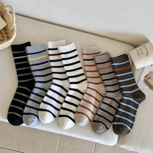 Close-up detail of various multi-colored striped mid-calf socks in a cozy lifestyle setting