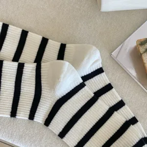 Close-up detail of white and black striped ribbed mid-calf socks with soft texture