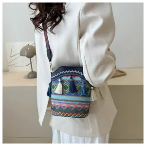 Detailansicht der gewebten Ethno-Beuteltasche mit bunten Quasten auf einem weißen Blazer