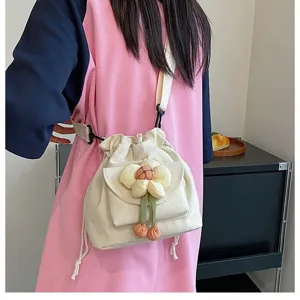 Nahaufnahme einer süßen Segeltuchtasche in Creme mit einer Plüschblume als Dekor