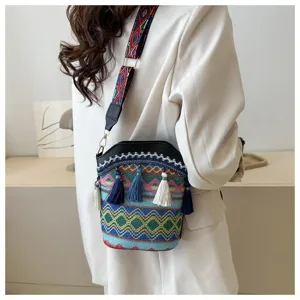 Boho-Eimertasche aus Webstoff mit bunten Quasten und geometrischem Riemen am Modell