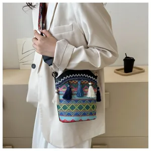Detail einer gewebten Eimertasche im Bohème-Stil mit Quasten, getragen von einem Model