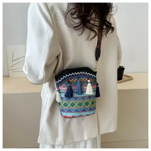 Detailansicht einer farbenfrohen Ethno-Eimertasche mit Quasten getragen auf Blazer