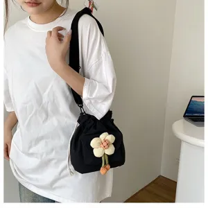 Detailansicht einer süßen schwarzen Segeltuchtasche mit Plüschblume, getragen von einem Model