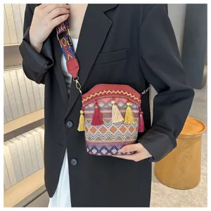 Detaillierte Ansicht einer gewebten Boho-Eimertasche mit bunten Quasten am Modell