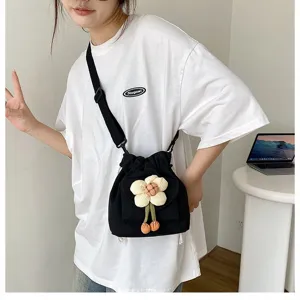 Detailansicht einer süßen schwarzen Canvas-Umhängetasche mit weißer Blume am Model