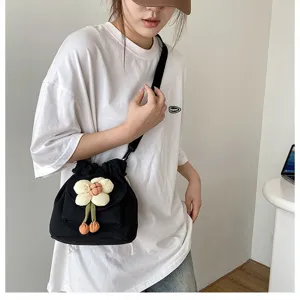 Süße schwarze Canvas Umhängetasche mit Plüschblumen-Anhänger an einem Model getragen