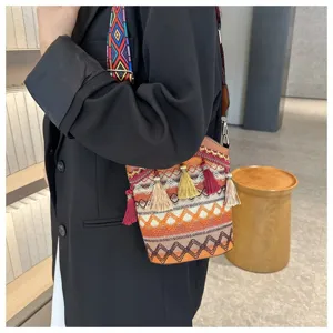 Detail einer Ethno-Beuteltasche mit bunten Quasten und breitem gemustertem Schultergurt.