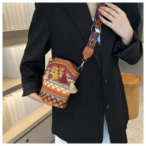 Ethnische gewebte Beuteltasche mit Quasten und buntem Gurt auf einem schwarzen Blazer getragen