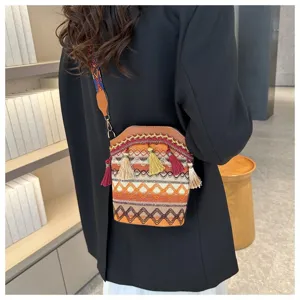 Detail einer Eimer-Tasche im Ethno-Stil mit bunten Quasten und geometrischen Mustern.