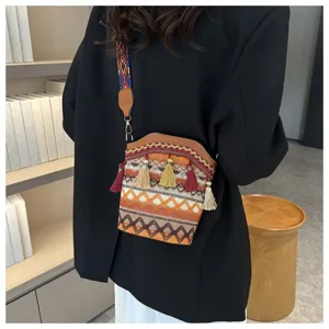Detailansicht einer Vintage-Ethno-Beuteltasche mit Quasten und buntem Riemen an einem Model
