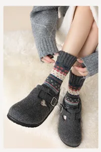 Nahaufnahme von Fair-Isle-Wollsocken mit grauen Clogs auf einem weichen Teppich
