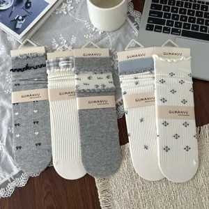 Detailed view of grey and cream floral socks with ruffle trim and bow accents on a desk.