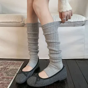 Detail view of grey ribbed leg warmers worn with ballet flats in a cozy indoor setting