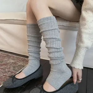Detailed macro view of grey ribbed slouchy leg warmers paired with grey ballet flats