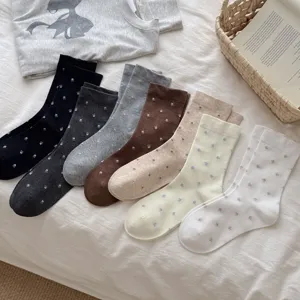 Close up view of cute floral mid-calf socks in assorted colors on soft cozy bedding background.