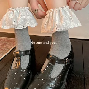 Nahaufnahme von grauen Damensocken mit weißer Spitzenrüsche und süßem Lolita-Design.