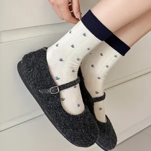 Close-up detail of women's floral mid-calf socks paired with dark grey Mary Jane shoes.