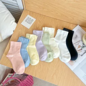 Vue détaillée de diverses chaussettes en coton de couleur pastel sur une surface en bois.
